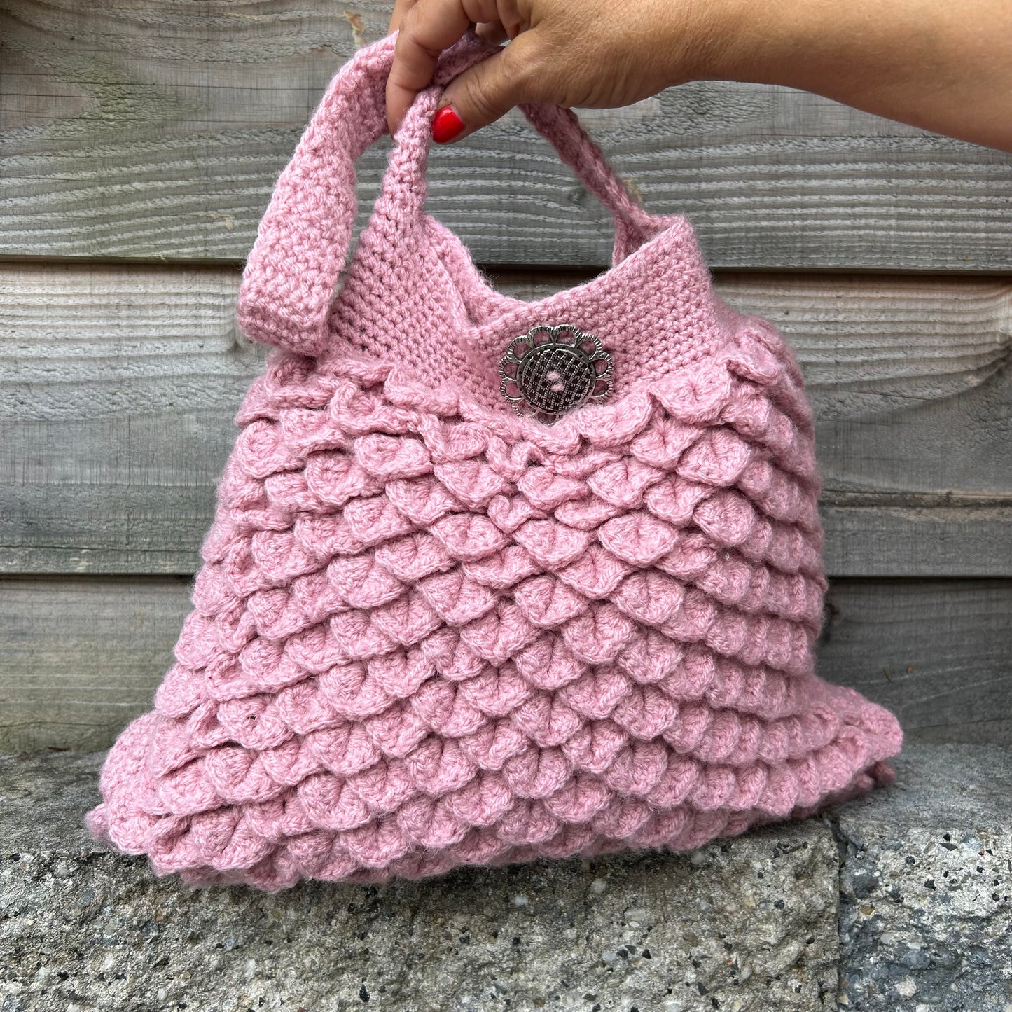 Hand houdt tas genaamd 'Grandma Pink' van S.E.V. Originals met roze hengsel, De Garengarage.