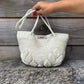 Hand houdt hengsel van Leaf tas 'Off White' van S.E.V. Originals, De Garengarage.